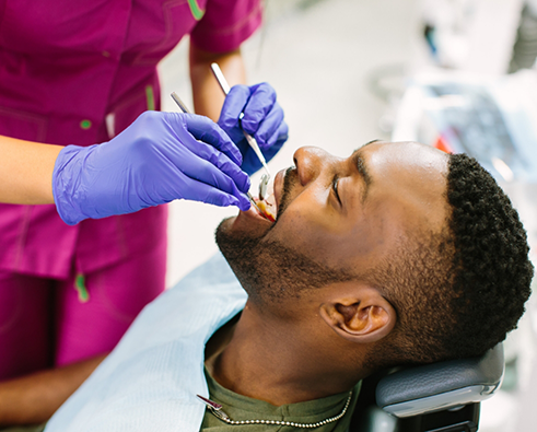 Male patient receiving dental cleaning for preventive dentistry