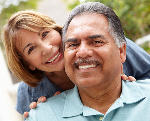 Smiling couple showcasing confidence and happiness after dental implant treatment, emphasizing restored smiles and improved quality of life.
