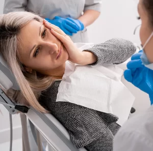 Patient experiencing tooth sensitivity in dental chair, consulting with dentist about winter-related dental issues and pain management.