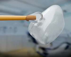 Dental veneer being held with a dental tool, showcasing its translucent appearance and design, relevant to cosmetic dentistry and smile enhancement.