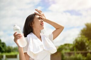woman sweating outside and holding bottle of water